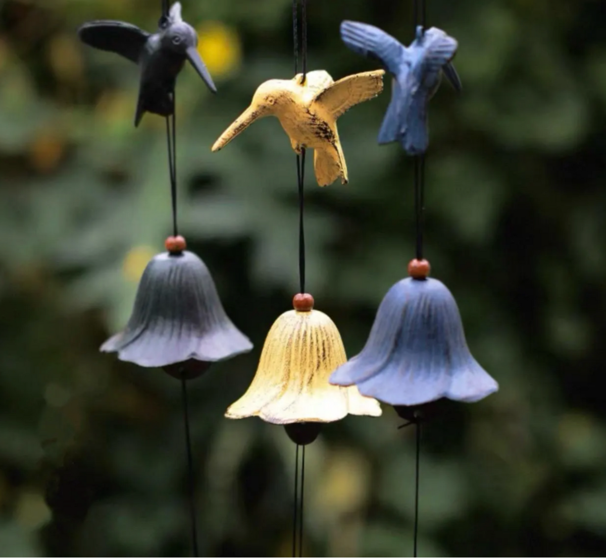 Assorted Japanese cast iron bird wind chimes in black, yellow, and blue hanging outdoors