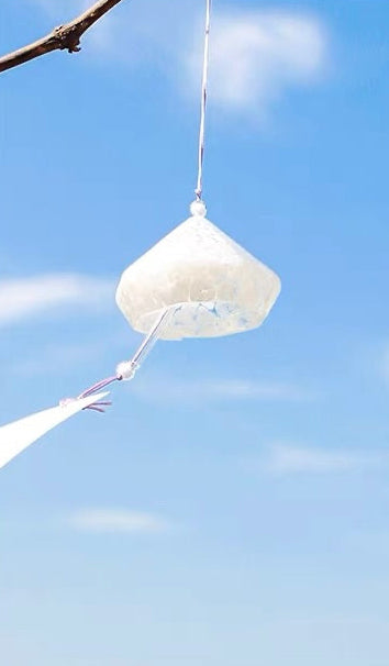 Handcrafted Japanese white diamond-shaped glass furin wind chime hanging outdoors.