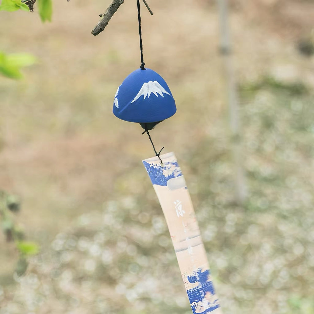 Handcrafted Japanese Mount Fuji cast iron furin wind chime hanging outdoors against a natural background.