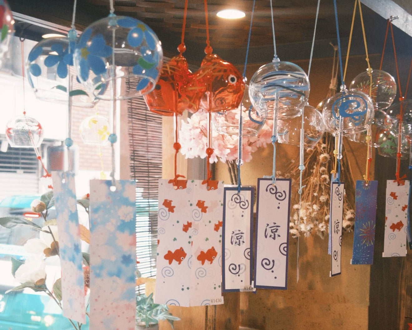 Japanese glass furin wind chimes displayed in a warm indoor shop setting with colorful tanzaku strips