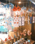 Collection of colorful Japanese glass furin wind chimes displayed indoors with patterned tanzaku strips