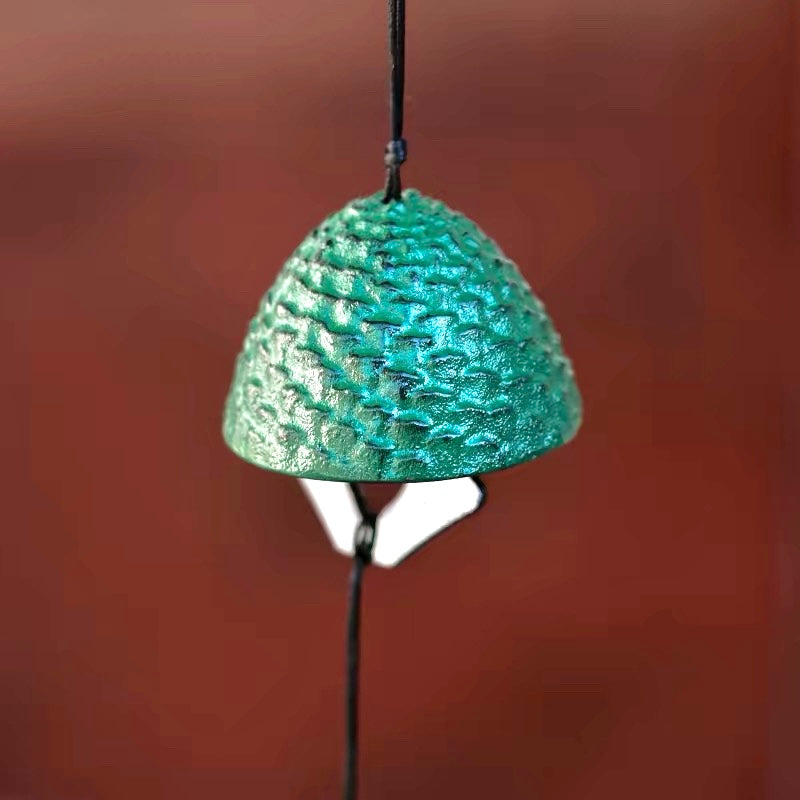 Close-up of a Japanese green cast iron pine cone furin wind chime with textured detail