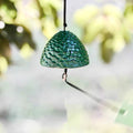 Japanese green cast iron pine cone furin wind chime hanging outdoors in a peaceful garden