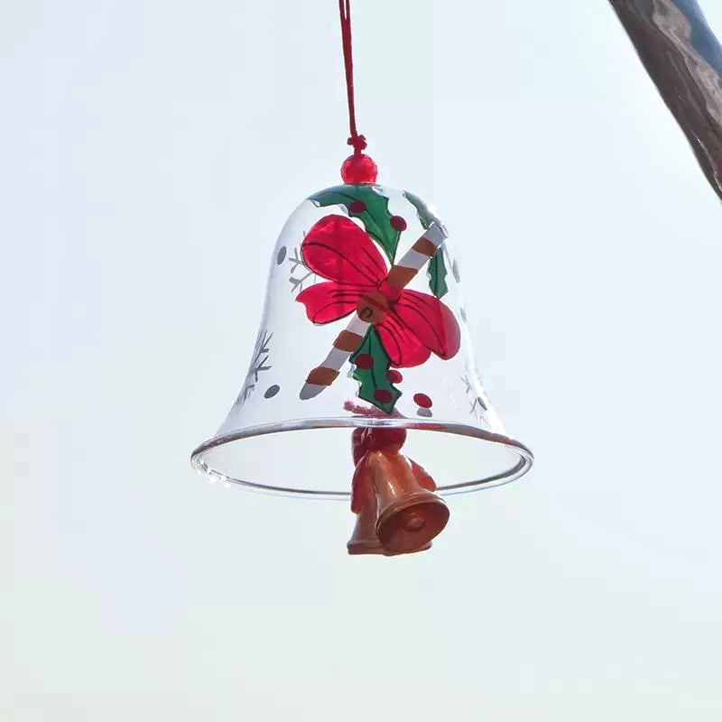 Red bell Christmas glass wind chime with bow and holly design hanging against a clear blue sky