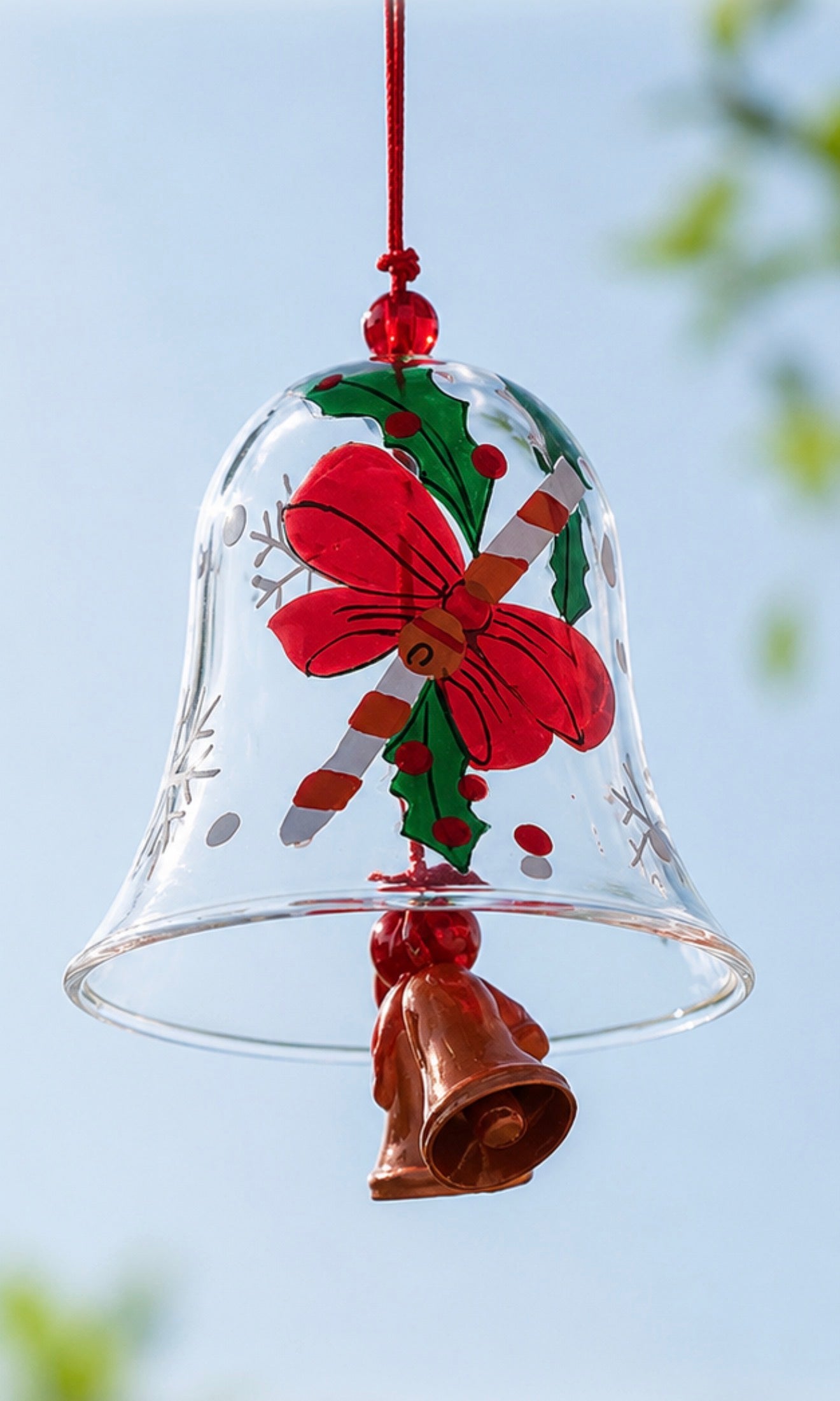 Close-up of a red bell Christmas glass wind chime with hand-painted bow and holly design