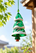 Green Christmas tree glass wind chime hanging in sunlight with maple leaves and holiday details