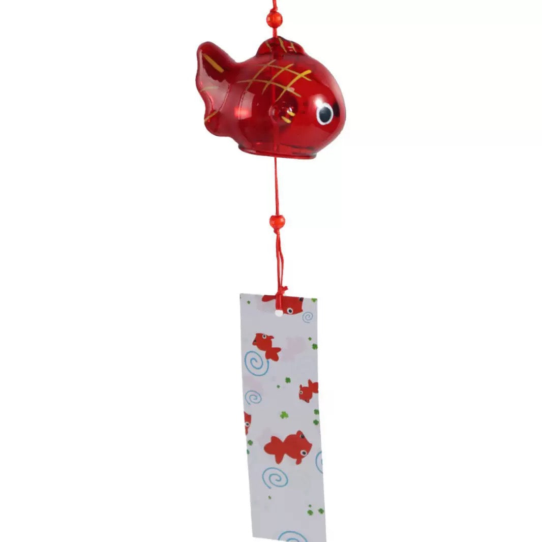 Red goldfish-shaped Japanese glass wind chime hanging with a patterned tanzaku strip