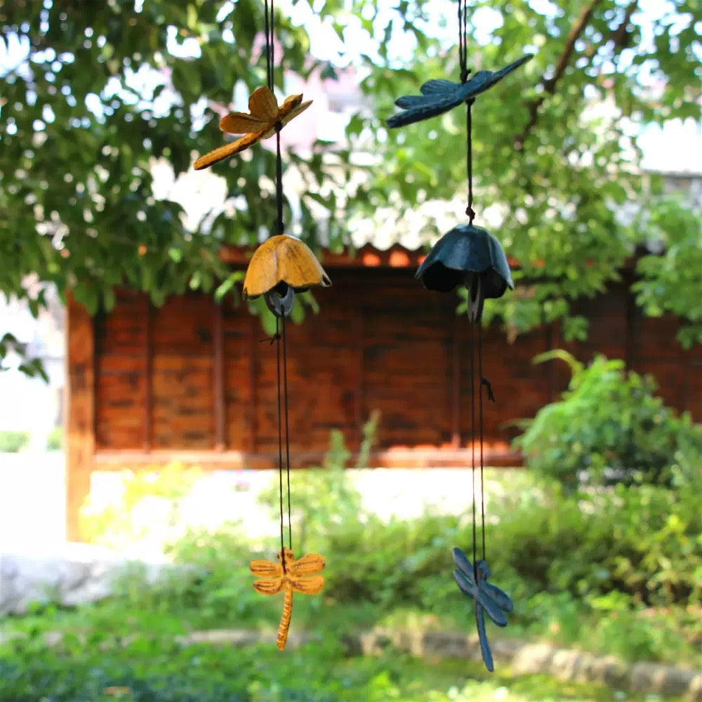 Blue and yellow dragonfly cast iron wind chimes hanging outdoors in a garden