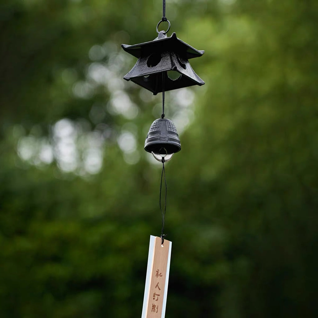 Japanese black cast iron pagoda furin wind chime hanging outdoors with wooden tanzaku strip