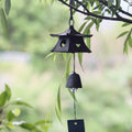 Japanese black cast iron temple pagoda furin wind chime hanging outdoors in a peaceful garden