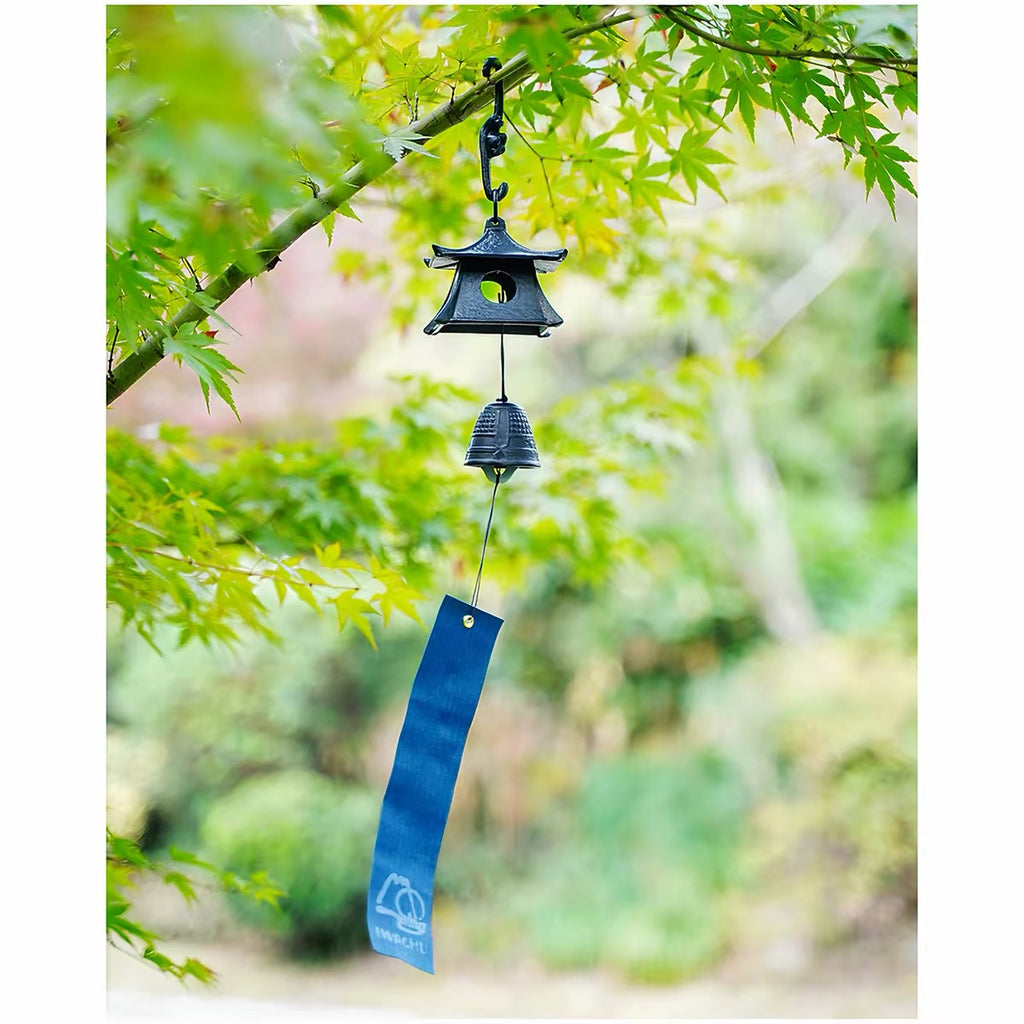 Japanese cast iron pagoda wind chime with blue tanzaku strip hanging under green maple leaves