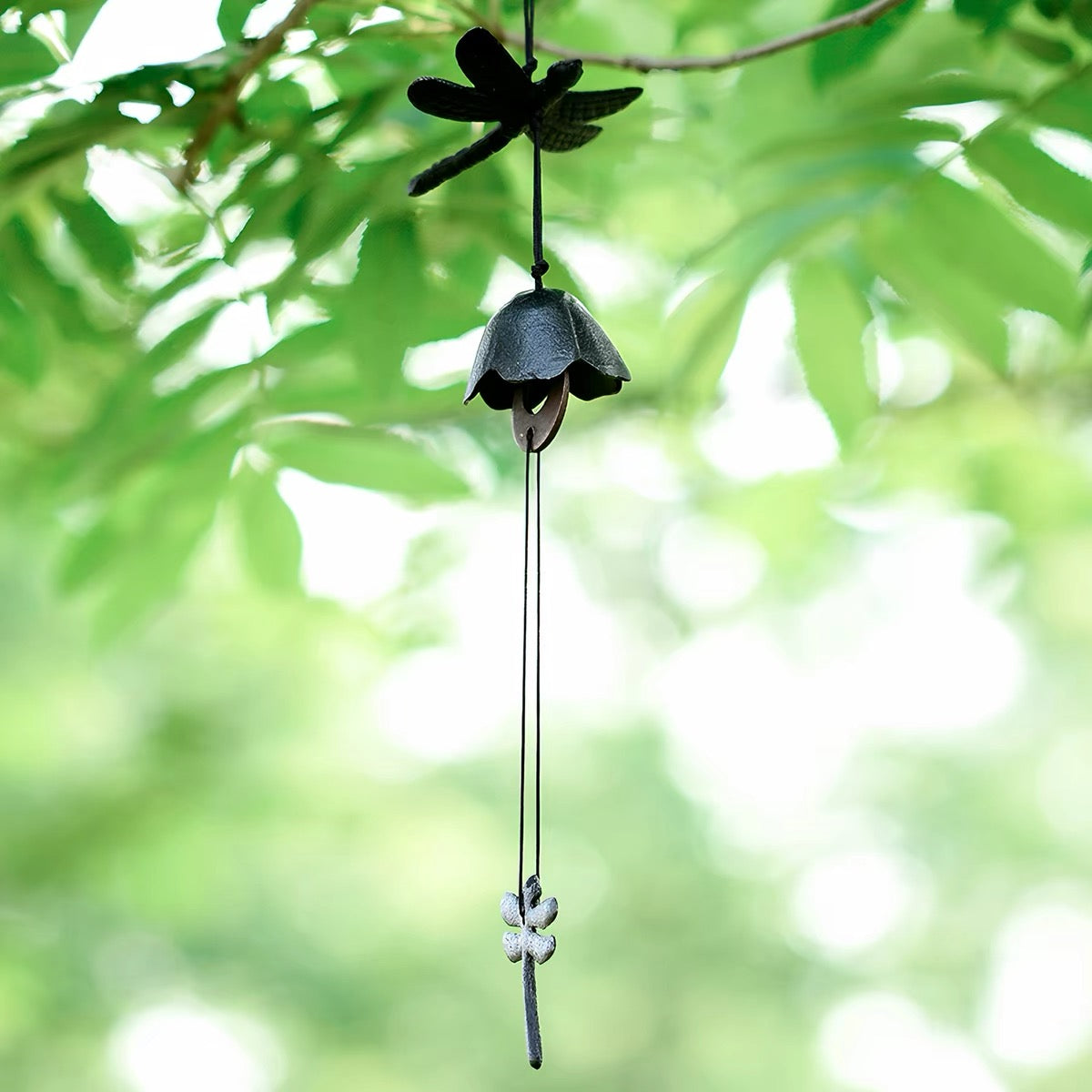 Dark Green dragonfly cast iron wind chime hanging under bright green leaves