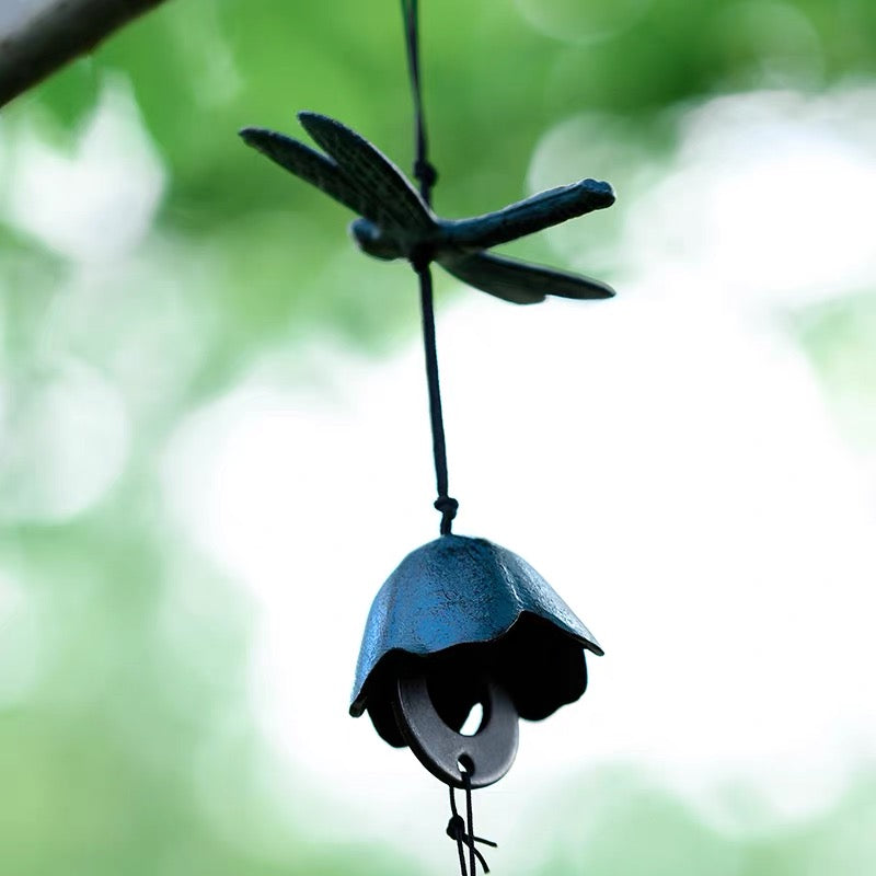 Blue dragonfly cast iron wind chime hanging under bright green leaves