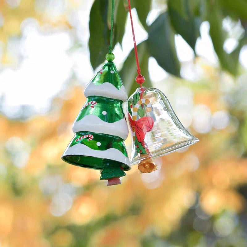 Christmas tree and red bell glass wind chimes hanging outdoors with festive holiday designs