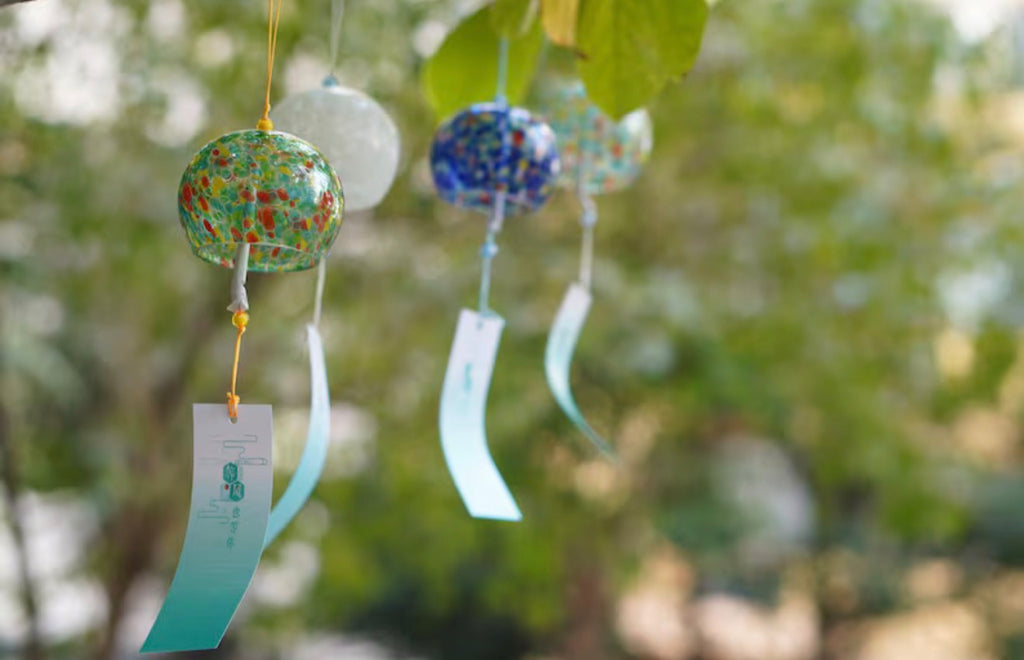 Colorful Japanese glass furin wind chimes hanging together beneath a tree