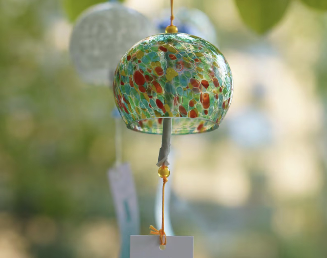 Close-up of a green multicolor Japanese glass furin wind chime in a garden