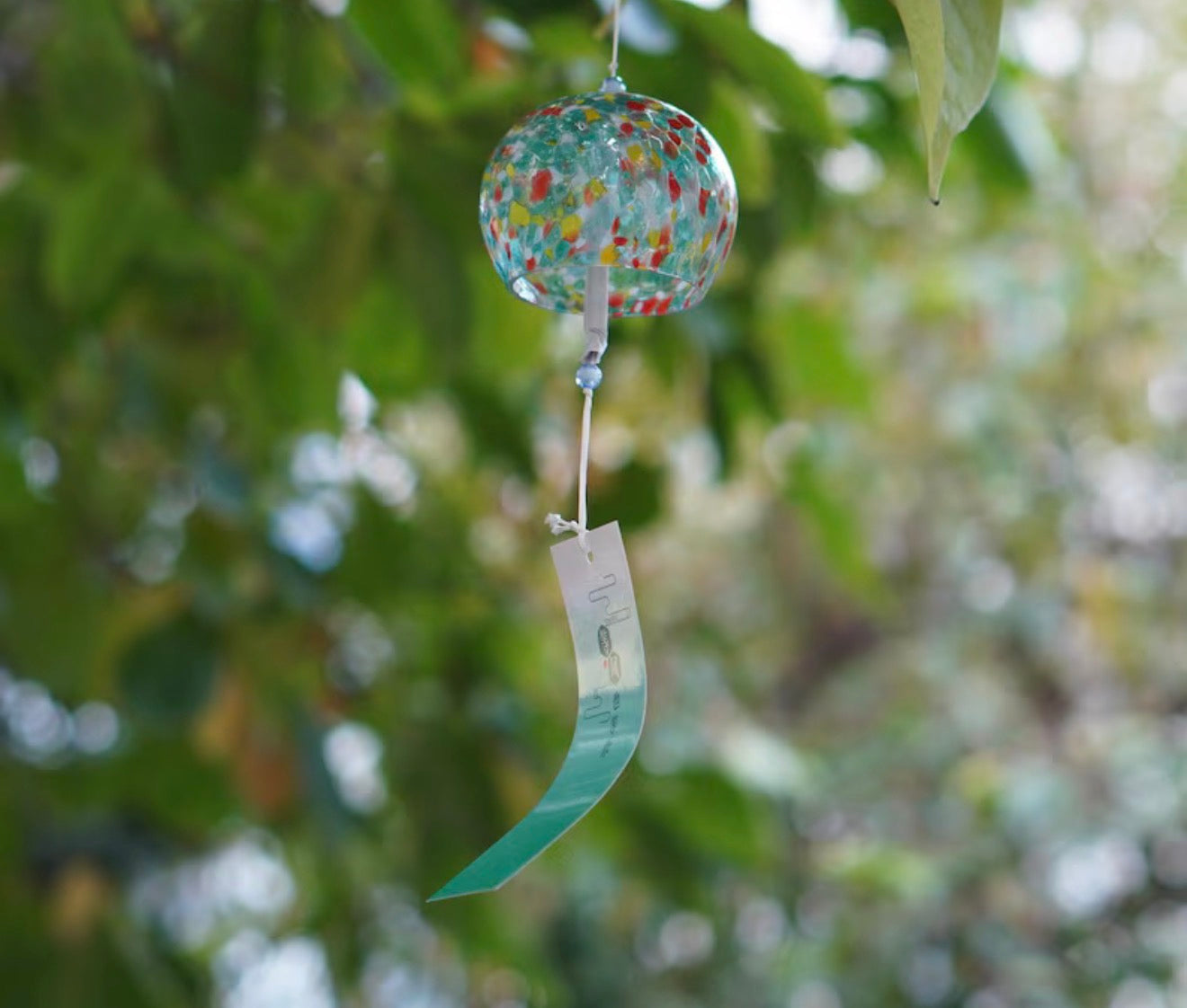 Green and red mosaic Japanese glass furin wind chime hanging outdoors