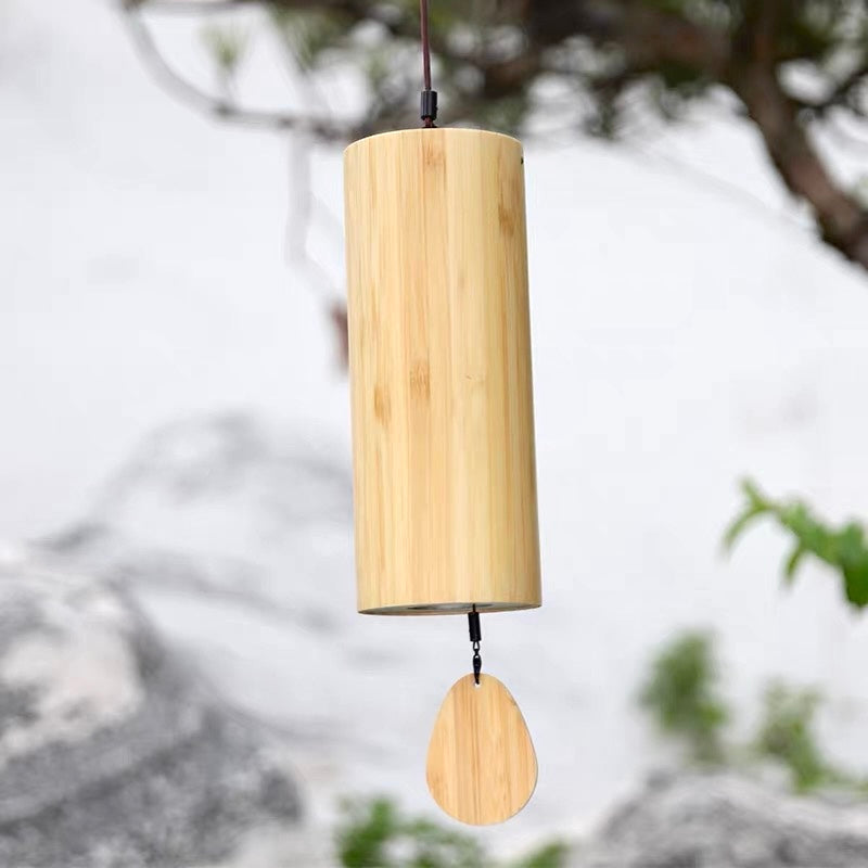 Japanese bamboo meditation wind chime hanging in a Zen garden with soft natural greenery and stone background.