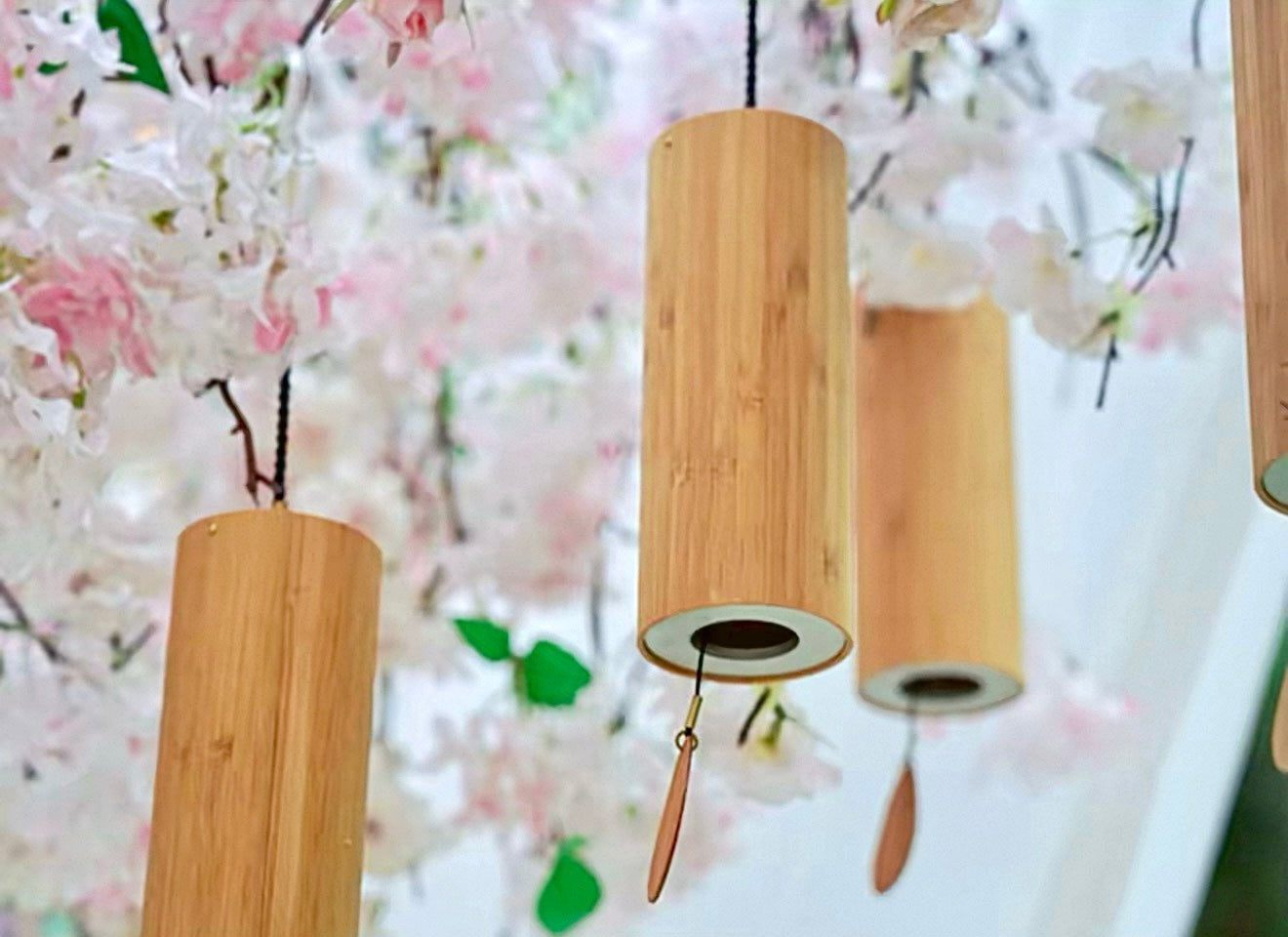 Japanese bamboo meditation wind chimes hanging beneath soft cherry blossoms for peaceful Zen-inspired decor.