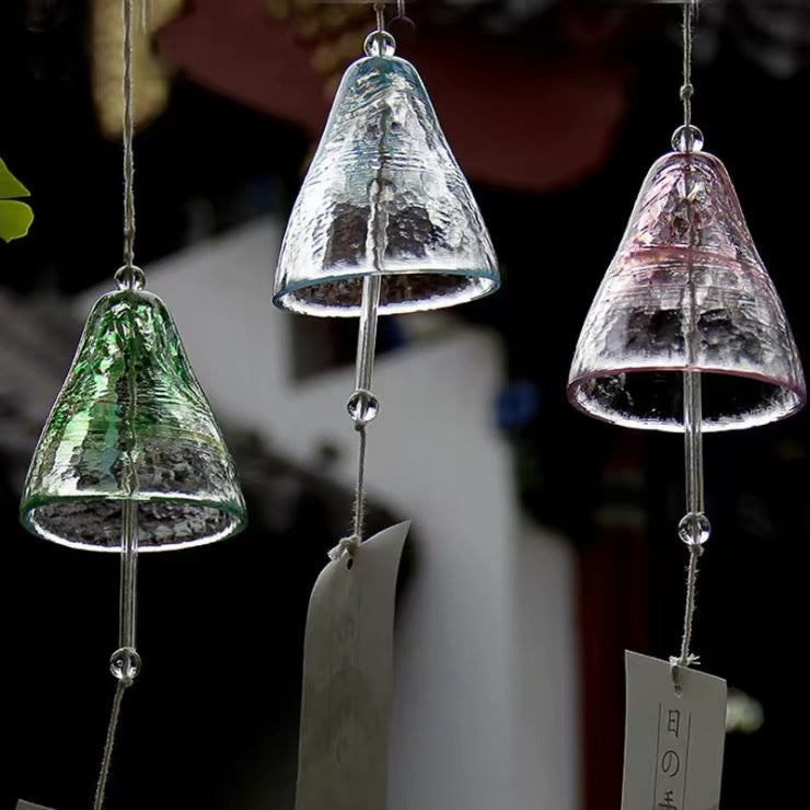 Japanese handmade thick glass furin wind chimes in green, blue, and pink hanging together in a peaceful outdoor setting.