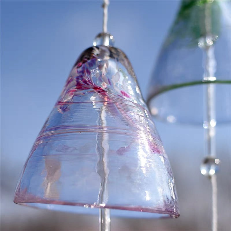 Close-up of a pink Japanese handmade thick glass furin wind chime with clear textured glass in soft sunlight.