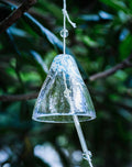 Close-up of a blue Japanese handmade thick glass furin wind chime hanging among green leaves.