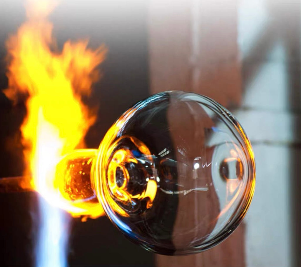 Close-up of a Japanese handmade thick glass wind chime being shaped by flame during the glassblowing process.