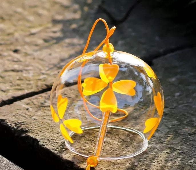 Japanese glass furin wind chime with yellow floral design displayed in warm sunlight