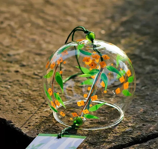 Japanese glass furin wind chime with orange osmanthus flower design displayed outdoors