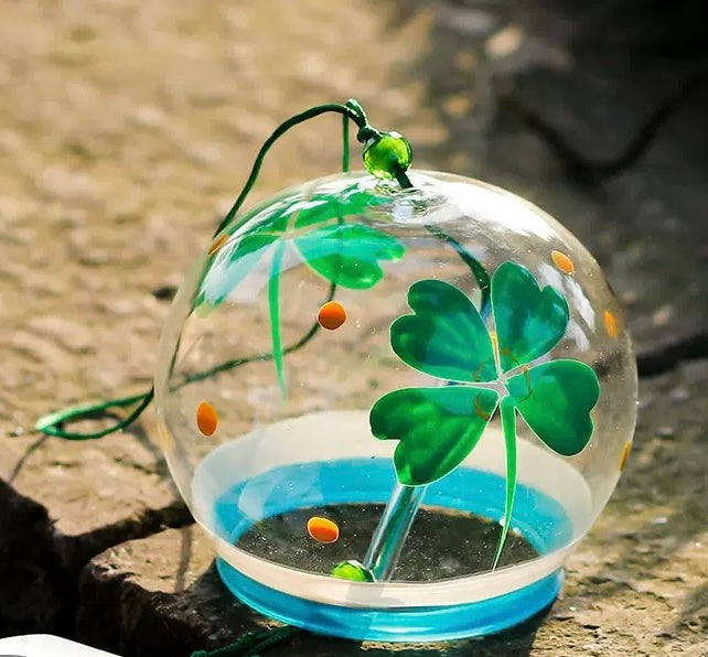 Japanese glass furin wind chime with green four-leaf clover design displayed in sunlight