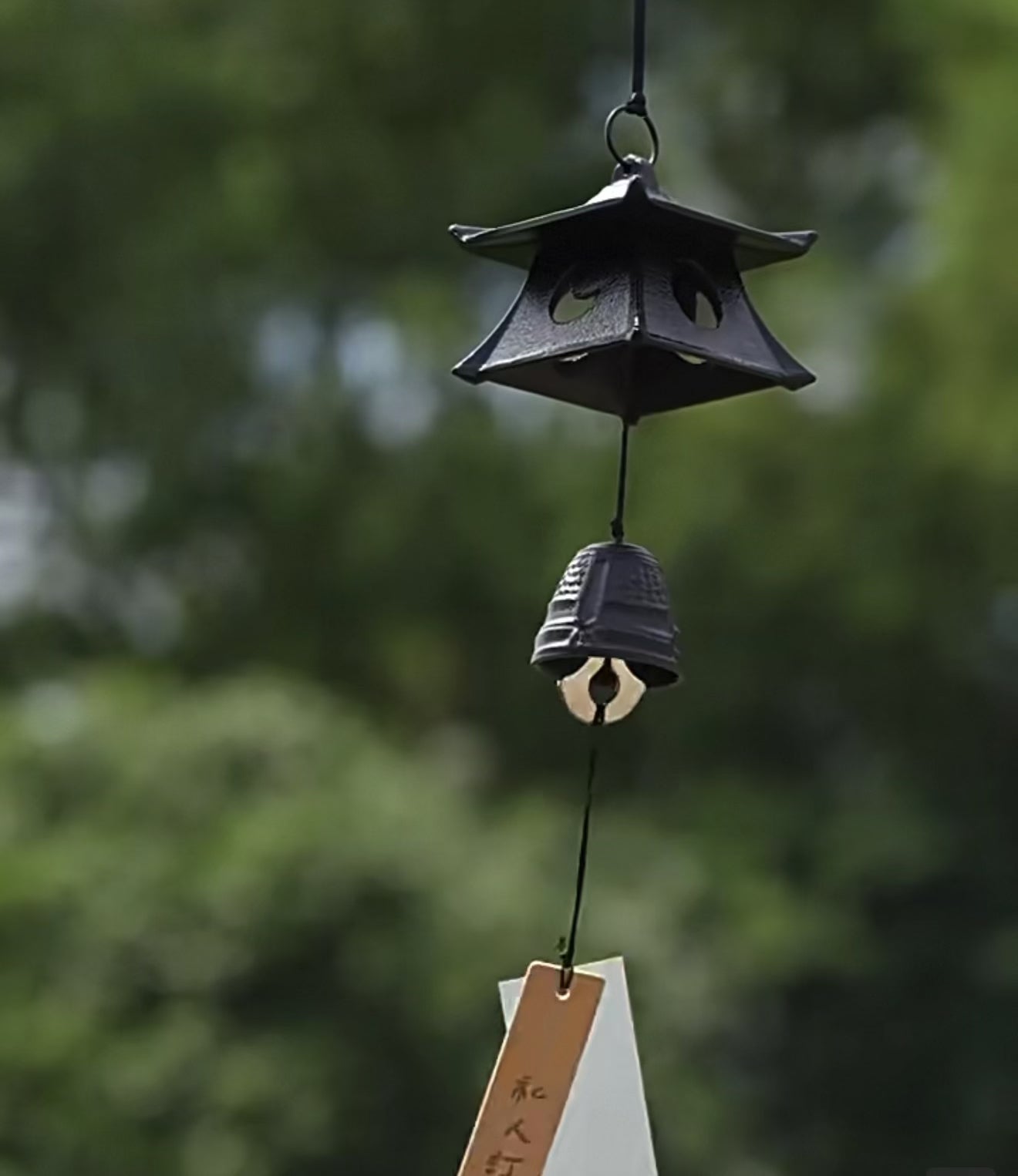 Video of a Japanese cast iron temple pagoda wind chime gently swaying outdoors